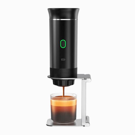 Black portable coffee maker dispensing coffee into a glass on a white background