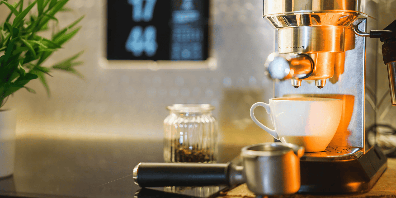 Espresso machine brewing a cup of coffee with a plant and digital display in the background.